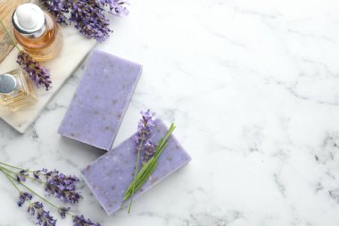 Sabun barları, diğer kozmetik ürünleri ve lavanta çiçekleri beyaz mermer masada, düz yerde. Metin için boşluk