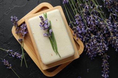 Aromatik sabun çubuğu ve lavanta çiçekleri koyu desenli masa, düz uzanmış