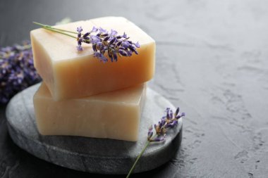 Aromatik sabun barları ve lavanta çiçekleri koyu dokulu masa üzerinde, yakın plan. Metin için boşluk