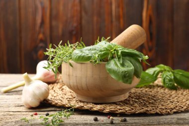 Kabuklu havan, farklı aromatik otlar ve baharatlar ahşap masada, yakın plan.