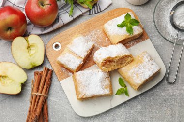 Lezzetli elmalı turta parçaları pudra şekerli ve nane şekerli açık gri masa, düz yatıyordu.