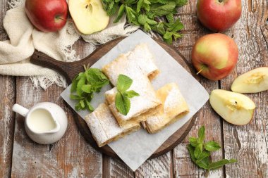Lezzetli elmalı turta parçaları pudra şekeri, nane ve ahşap masa üzerinde meyve, düz uzanmış