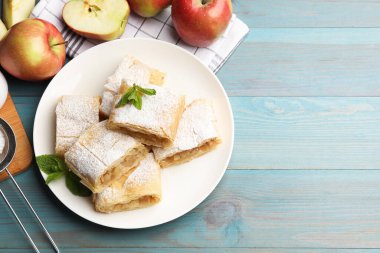 Pudra şekerli, nane şekerli ve açık mavi ahşap masada meyveli elmalı turta. Metin için boşluk