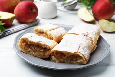 Lezzetli elmalı turta parçaları pudra şekeri ve beyaz mermer masada meyveler, yakın plan.