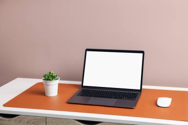 İçerideki beyaz masada dizüstü bilgisayarı ve turuncu faresi olan şık bir iş yeri. Metin için boşluk