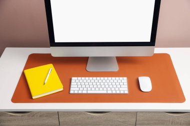 Beyaz masa üzerinde bilgisayar ve turuncu fare reklamı olan şık bir iş yeri, yakın plan.