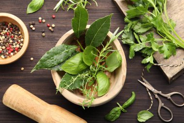 Tahta masada farklı taze otlar ve biberli havan topu.