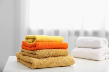 İçerideki beyaz masada renkli havlu yığını.