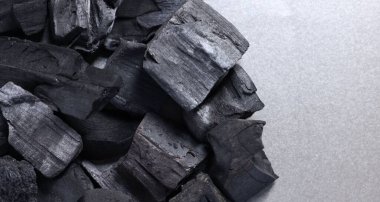 Gri masa üzerinde siyah kömür parçaları, üst manzara. Metin için boşluk