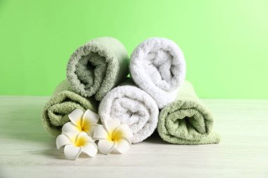 Taze havlular ve beyaz ahşap masadaki tesisat çiçekleri.