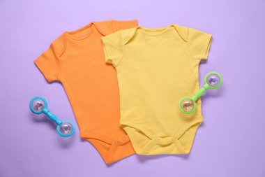 Mor arka planda parlak bebek tulumları ve aksesuarları düz yatıyordu.