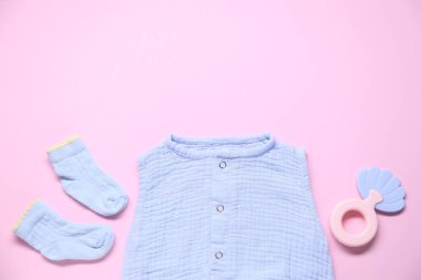 Pembe arka planda bebek kıyafetleri ve aksesuarlar, düz yatış. Metin için boşluk