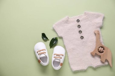 Açık yeşil arka planda bebek kıyafetleri ve aksesuarlar, düz yatış. Metin için boşluk