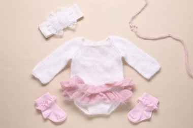 Bej arka planda bebek kıyafetleri ve aksesuarlar, düz yatış