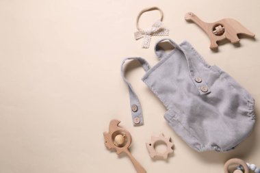 Bej arka planda bebek tulumu ve aksesuarlar, düz yatış. Metin için boşluk