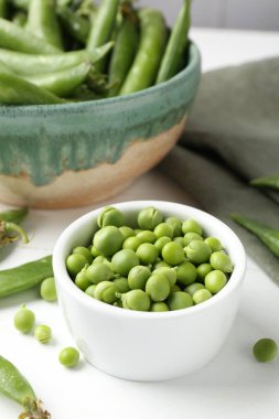 Taze taze bezelyeler beyaz ahşap masada, yakın plan.