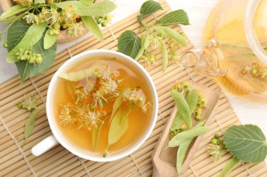 Taze ıhlamur çayı, çaydanlık ve çiçekler beyaz ahşap masada, düz uzanmış