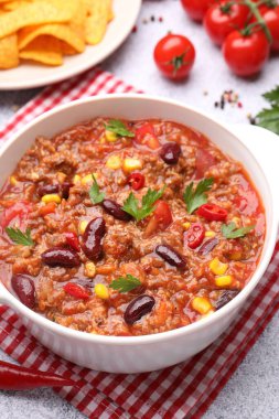 Lezzetli biberli makarna kasede, nachos ve malzemeler gri masada, yakın plan.