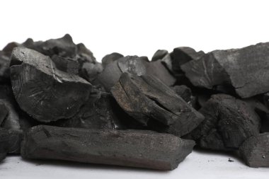 Beyaz arkaplanda siyah kömür parçaları