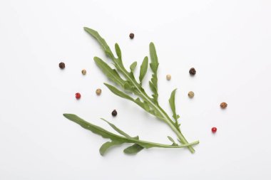 Taze yeşil roka yaprakları ve beyaz arka planda biberler, düz yatıyordu.