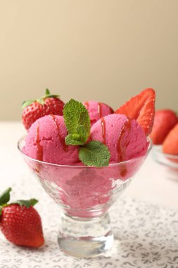 Şerbeti şerbetle, çilekle ve nane şekeriyle bej arka planda beyaz masada yeniliyor.