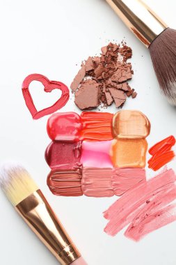 Beyaz arka planda farklı kozmetik ürünler ve makyaj fırçaları, düz yatış