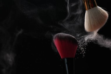 Siyah arka planda kozmetik tozlu makyaj fırçaları, yakın plan. Metin için boşluk