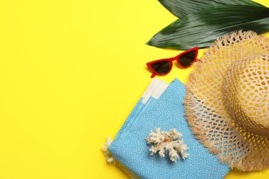 Plaj havlusuyla düz kompozisyon ve sarı arka planda diğer yaz aksesuarları. Metin için boşluk