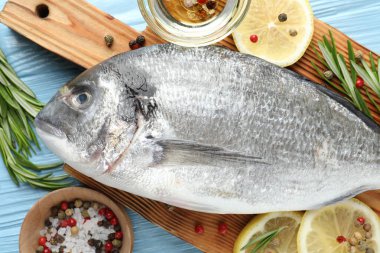 Mavi ahşap masadaki baharatlı taze çiğ dourade, yakın plan. Balık ve deniz ürünleri lezzetleri