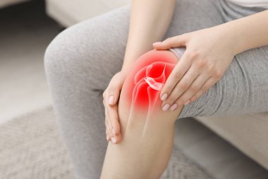 Artrit. Kapalı koltukta dizinde ağrıdan muzdarip bir kadın, yakın plan. Bacağında eklem iltihabı var.