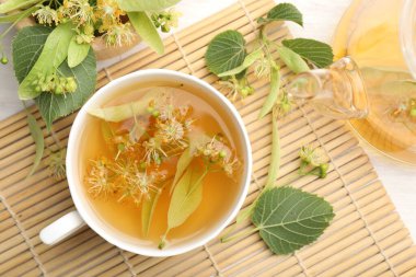 Taze ıhlamur çayı, çaydanlık ve çiçekler beyaz ahşap masada, düz uzanmış