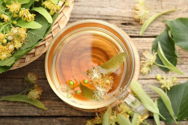 Fincanda nefis ıhlamur çayı, ahşap masada yapraklar ve çiçekler, düz uzanmış