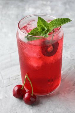 Buzlu vişneli gazoz, böğürtlen ve nane. Gri desenli masa, yakın plan.