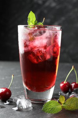 Buzlu vişneli gazoz, böğürtlen ve nane şekeri gri masada, yakın plan.
