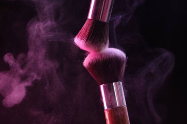 Renkli göz gölgeli makyaj fırçaları siyah arka planda neon ışıkları, yakın plan