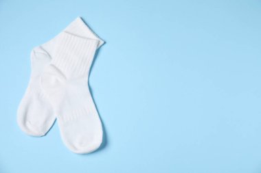 Açık mavi arka planda bir çift rahat beyaz çorap, üst manzara. Metin için boşluk