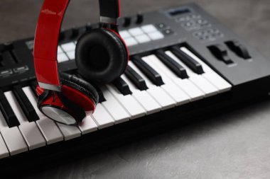 MIDI klavye ve kulaklıklar gri masada, yakın plan.