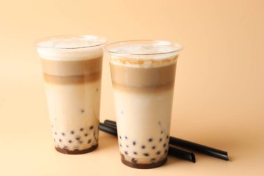 Bej arka planda plastik bardakta lezzetli sütlü çay, yakın plan.