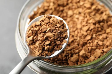 Gri arka planda hazır kahve ve kavanozlu kaşık, yakın plan.