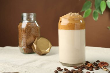 Bardakta lezzetli dalgona kahvesi, fasulye, ceviz ve granüller masada, yakın plan.