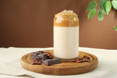 Bardakta lezzetli dalgona kahvesi, masada çikolata ve ceviz parçaları.