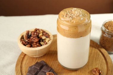 Bardakta lezzetli dalgona kahvesi, çikolata parçaları, ceviz ve granüller masada, yakın plan.