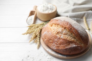 Bir somun taze ekmek, un ve çiviler beyaz ahşap masada, yakın plan. Metin için boşluk