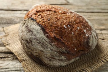 Tahta masada bir somun taze ekmek, yakın plan.