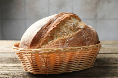 Hasır sepetin içinde bir somun taze ekmek, ahşap masanın üstünde, yakın plan.