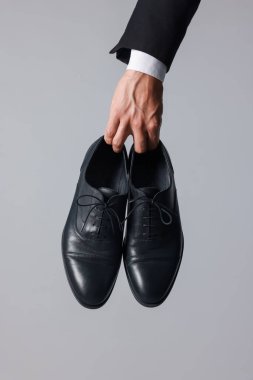 Açık arkaplanda siyah deri ayakkabı giyen bir adam, yakın plan.