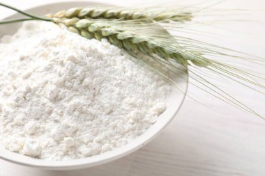 Yeşil buğday başakları ve un açık ahşap masada, yakın plan.