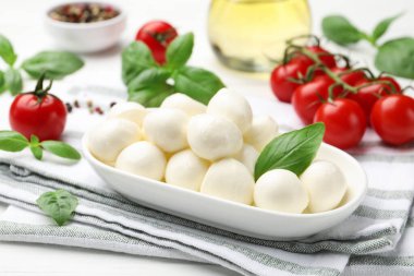 Lezzetli mozzarella peyniri, domates, fesleğen ve baharatlar beyaz masada, yakın plan.