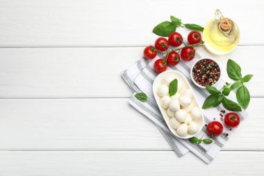 Lezzetli mozzarella peyniri, domates, fesleğen ve baharatlar beyaz ahşap masa, düz yatak. Metin için boşluk