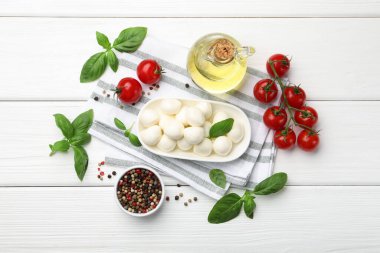 Lezzetli mozzarella peyniri, domates, fesleğen ve baharatlar beyaz ahşap masa üzerinde, düz yatıyordu.